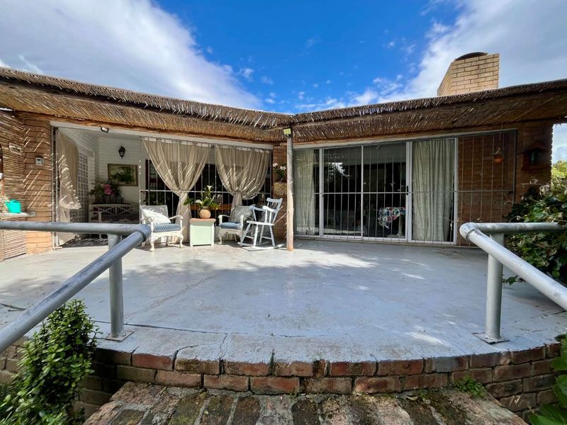 Covered outdoor patio area featuring a concrete floor, brick chimney, and sliding glass doors with security gates, offering a potential space for outdoor living.