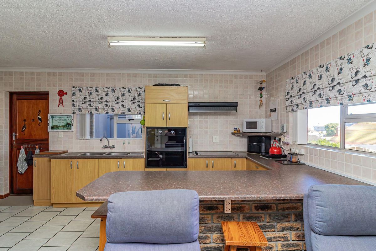 A functional kitchen featuring built-in cabinetry, a double sink, integrated oven, and a brick-based breakfast bar with tiled flooring and backsplash.
