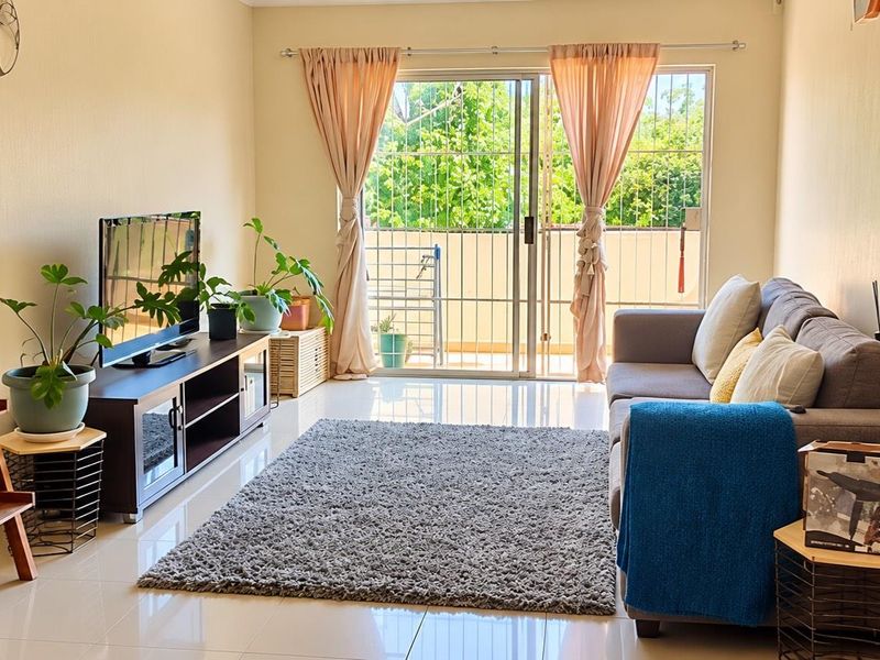 A bright living room featuring tiled flooring and a large sliding glass door that provides access to an outdoor area.