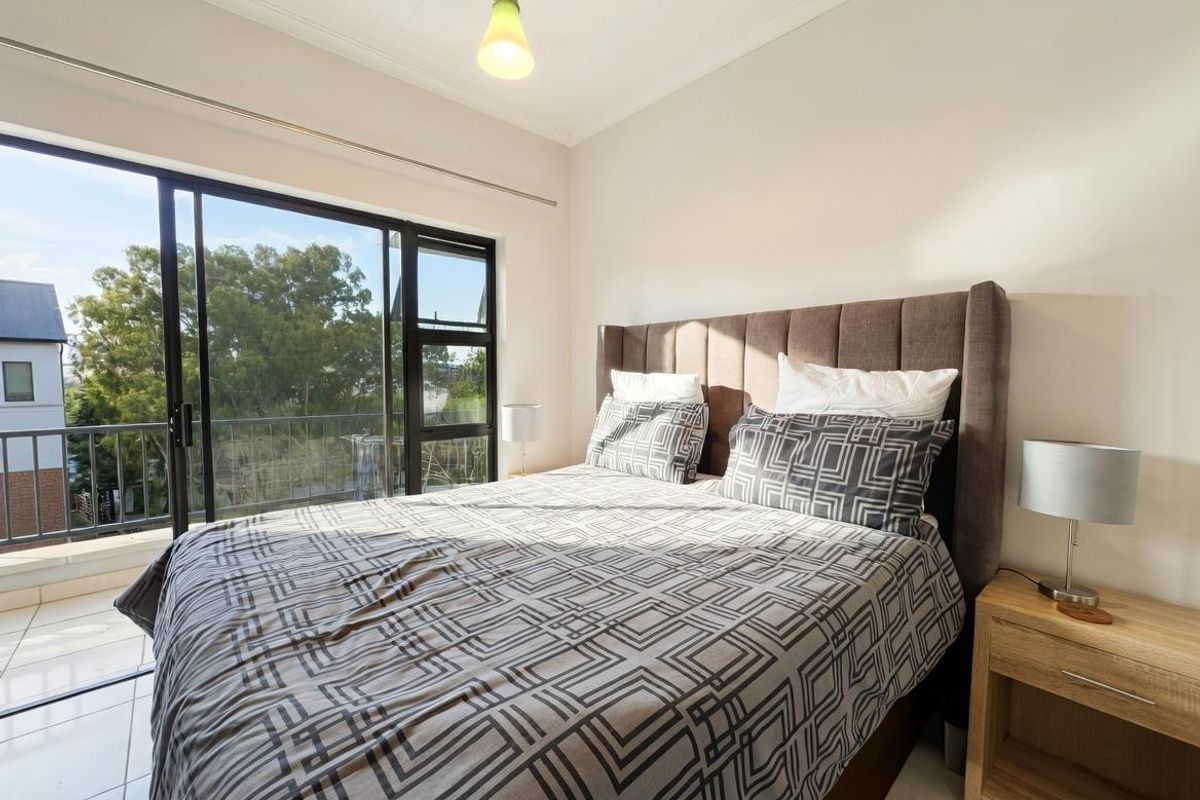 A bright bedroom featuring large sliding glass doors that open onto a private balcony, providing natural light and outdoor access.