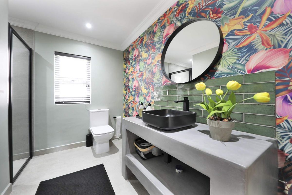Modern bathroom featuring a concrete vanity with a black vessel sink, walk-in shower, and vibrant floral feature wall.
