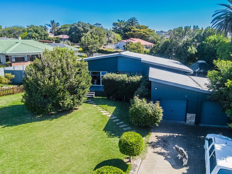 Aerial view of a modern residential property featuring a double garage, paved driveway, and a well-maintained garden with mature trees.