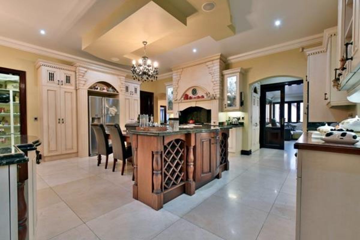 Spacious gourmet kitchen featuring custom cabinetry, a large central island with integrated wine storage, stone countertops, and high-end built-in appliances.