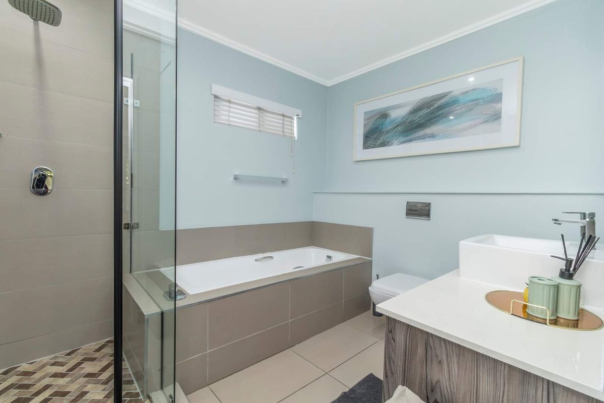 Modern bathroom featuring a walk-in shower, built-in bathtub, wall-mounted toilet, and a vanity with a basin.
