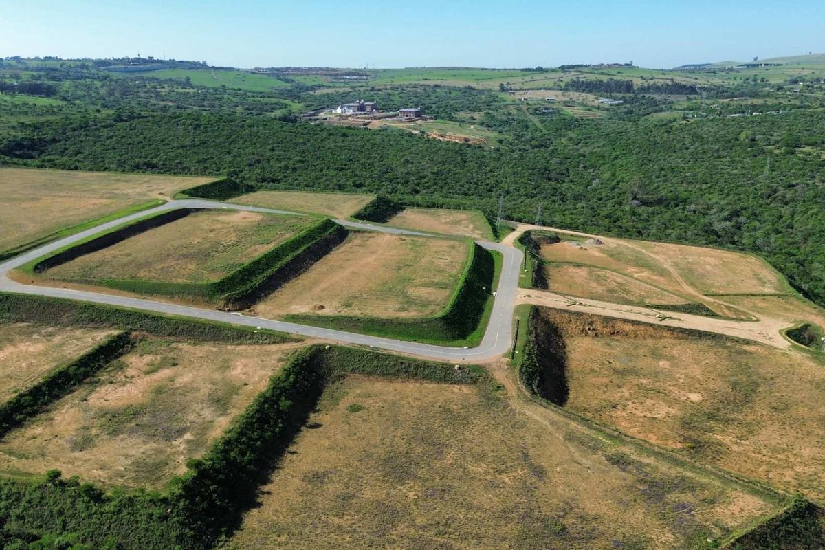 Aerial view of an industrial development site featuring prepared terraced platforms, paved internal road infrastructure, and surrounding natural landscape.