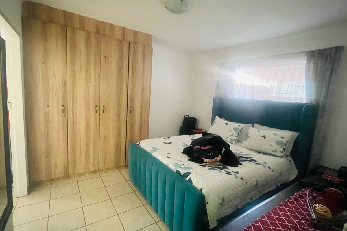 A bedroom featuring built-in wooden cupboards and tiled flooring, providing functional storage space.