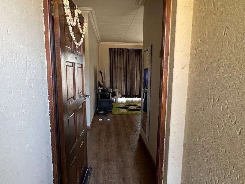 Entryway leading into the living area, featuring laminate flooring and a traditional timber door.