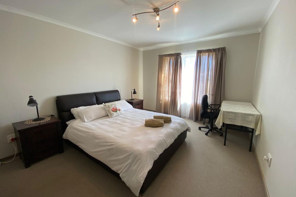 A spacious bedroom featuring neutral carpeting, coved ceilings, and a large window with curtains, providing a comfortable and functional living space.