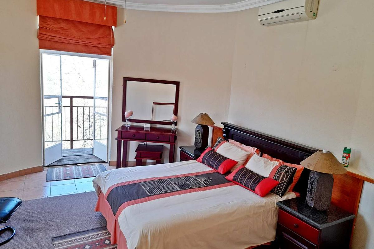 Spacious bedroom featuring a wall-mounted air conditioning unit, crown molding, and direct access to a private balcony through double doors.