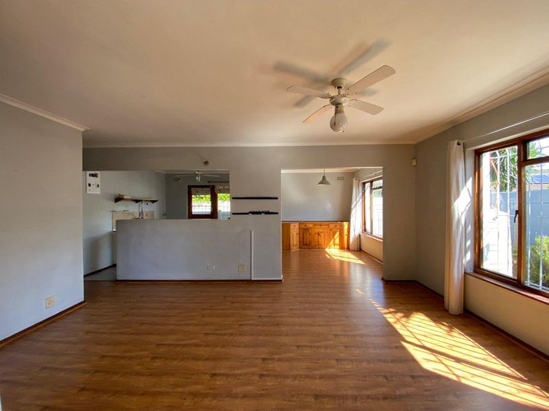 Spacious open-plan living area featuring laminate flooring, a ceiling fan, and built-in cabinetry, offering a bright and versatile layout.