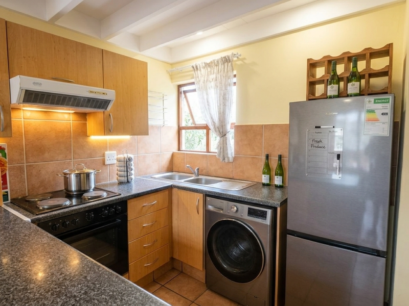 Functional kitchen featuring laminate cabinetry, tiled backsplash, built-in oven with extractor fan, and integrated space for laundry appliances.
