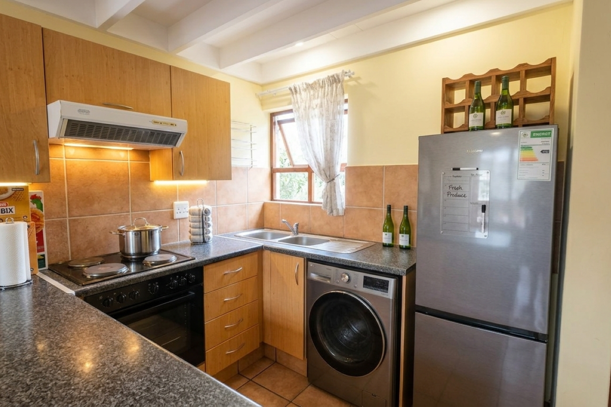 Functional kitchen featuring laminate cabinetry, tiled backsplash, built-in oven with extractor fan, and integrated space for laundry appliances.