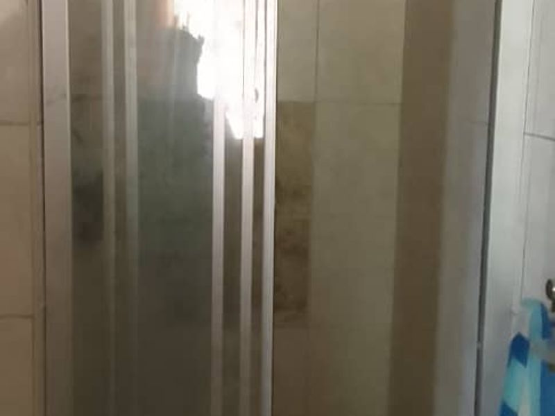 A functional shower cubicle featuring a sliding glass door and tiled wall finishes within a bathroom setting.