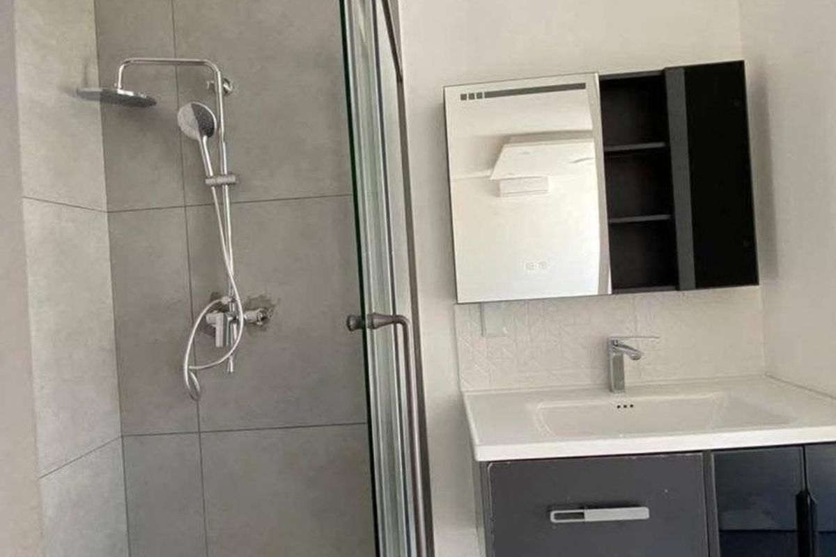 Modern bathroom featuring a walk-in shower with glass screen, wall-mounted vanity with basin, and integrated medicine cabinet.