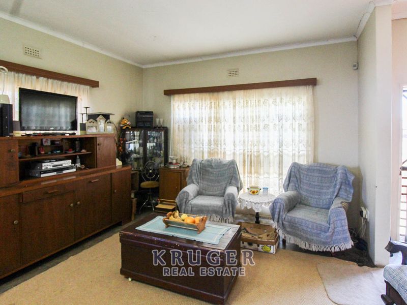 A living room area featuring neutral wall finishes, curtain rails, and a security gate leading to the exterior.