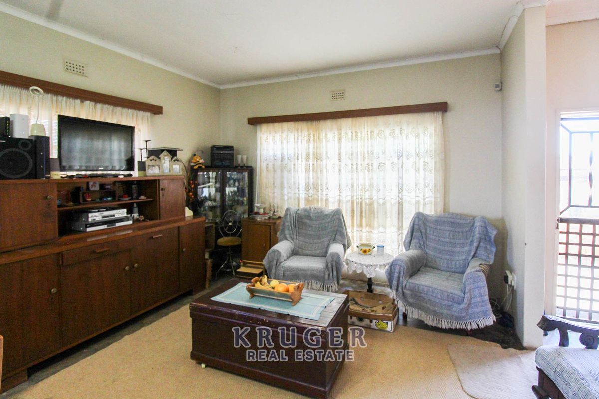 A living room area featuring neutral wall finishes, curtain rails, and a security gate leading to the exterior.