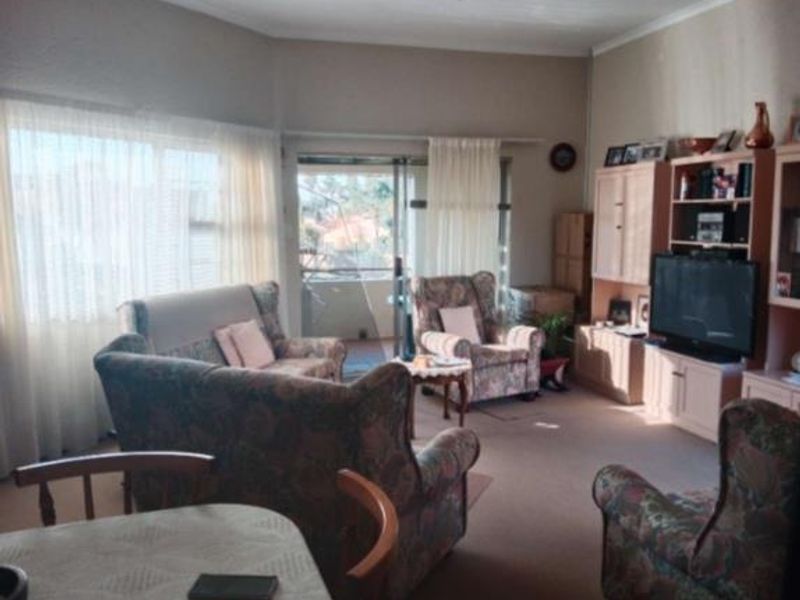 A spacious living room featuring carpeted flooring, built-in cabinetry, and a sliding glass door providing access to an outdoor balcony area.