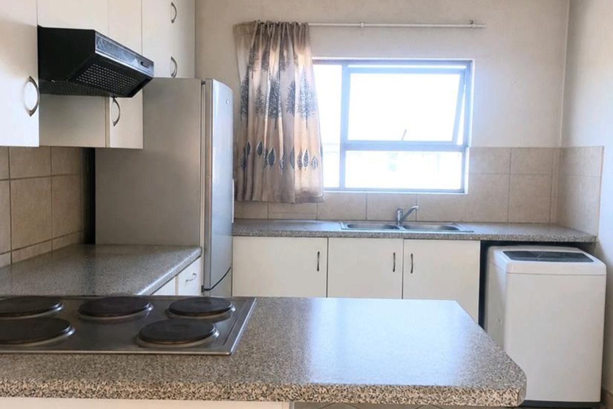 Functional kitchen featuring white cabinetry, laminate countertops, an electric hob with extractor fan, and tiled flooring with a double bowl sink.