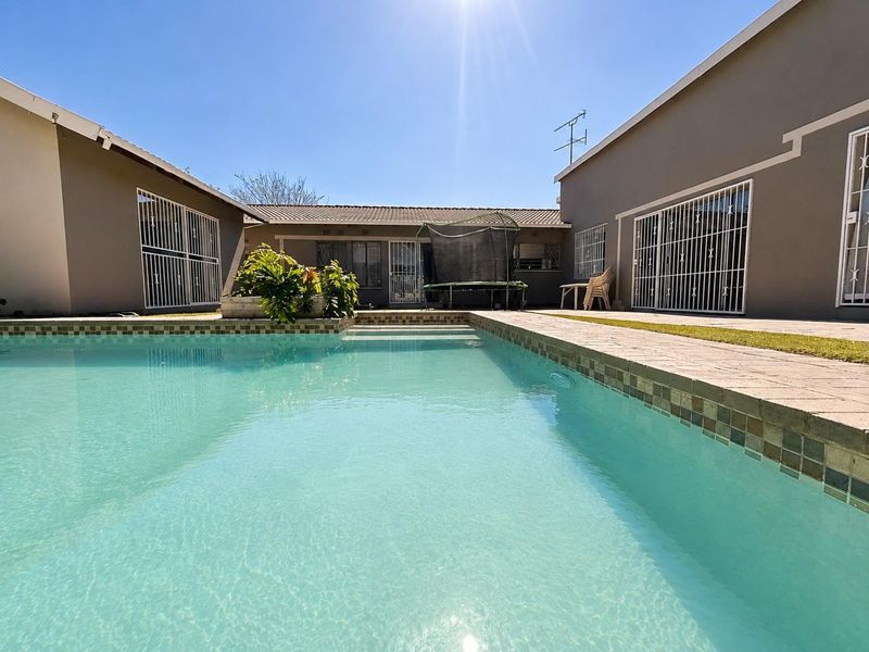 A well-maintained swimming pool area featuring paved surrounds and secure access to the main house structure.