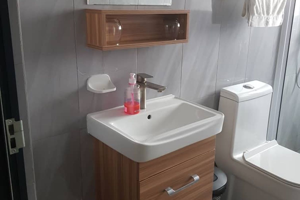 A modern bathroom featuring a wall-mounted vanity with basin, chrome fixtures, a dual-flush toilet, and neutral grey wall and floor tiling.