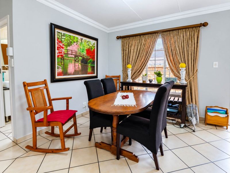 A well-maintained dining room featuring neutral tiled flooring, crown molding, and natural light through window blinds.