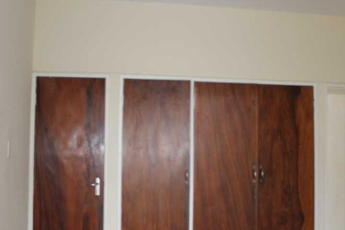 A bedroom featuring built-in wooden cupboards and carpeted flooring, offering a blank canvas for potential interior updates.