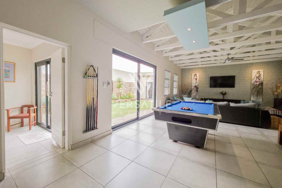 Spacious living area featuring a high exposed beam ceiling, tiled flooring, and large sliding glass doors providing seamless access to the outdoor space.
