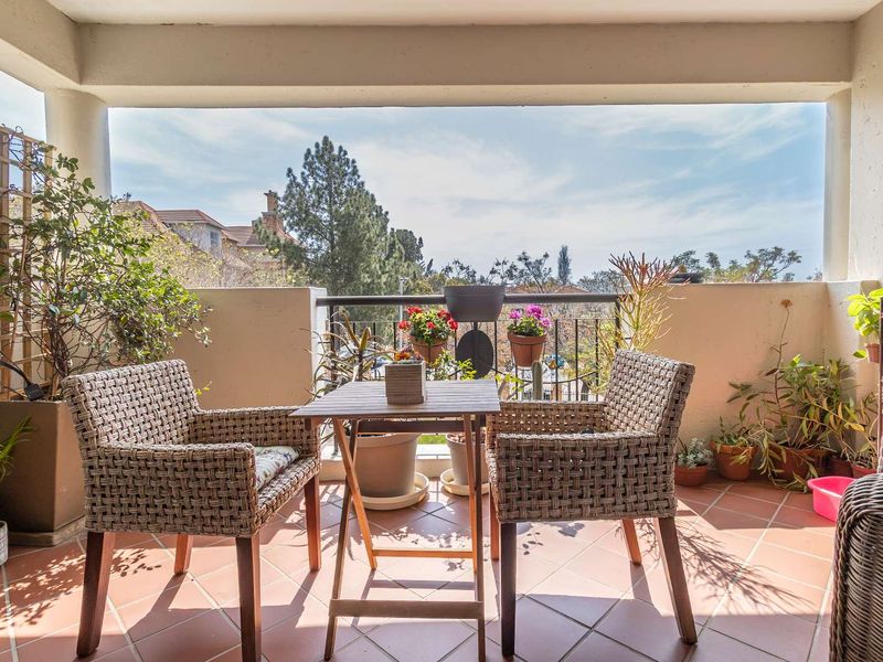 A covered balcony featuring tiled flooring and a metal balustrade, offering an open outdoor space with neighborhood views.