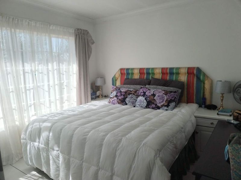 A bedroom featuring tiled flooring and a sliding glass door that provides natural light.