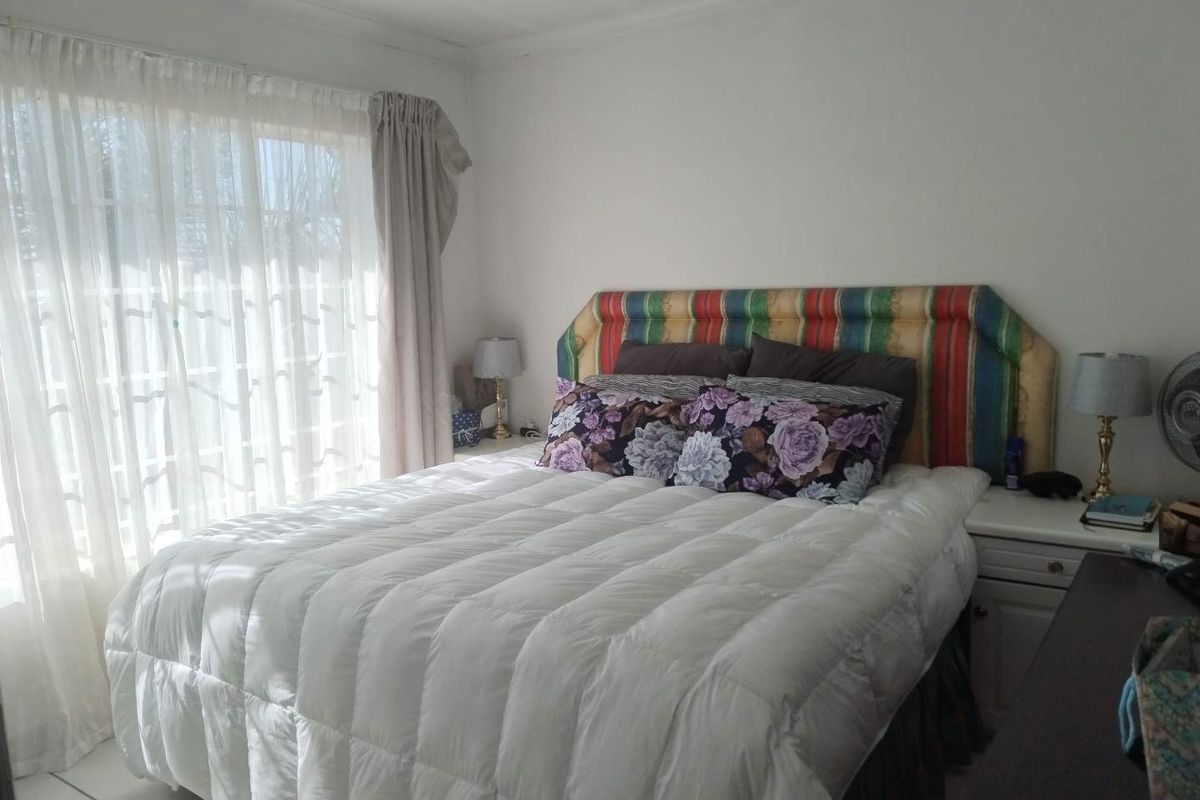 A bedroom featuring tiled flooring and a sliding glass door that provides natural light.