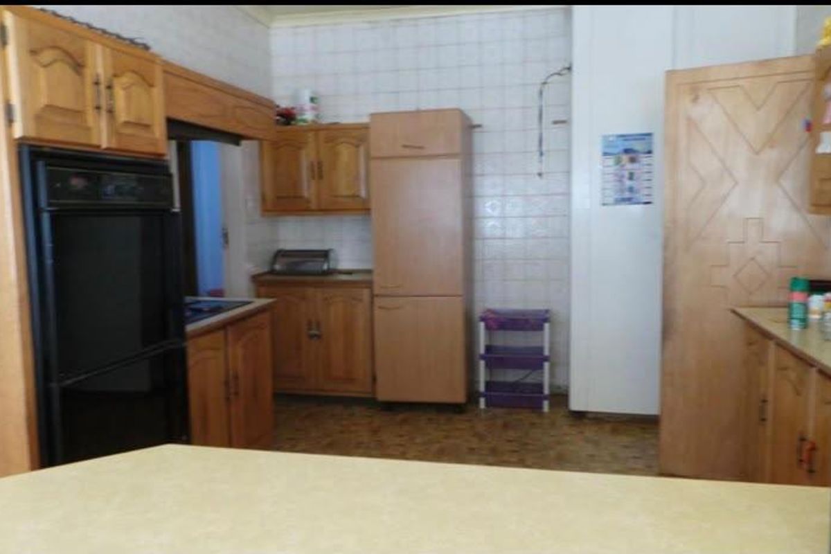 A dated kitchen featuring traditional wood-look cabinetry, built-in oven, and tiled backsplash, offering significant potential for a modern renovation.