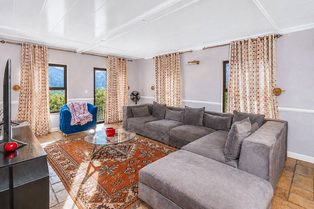 Spacious living room featuring large windows with mountain views, tiled flooring, and classic crown molding details.