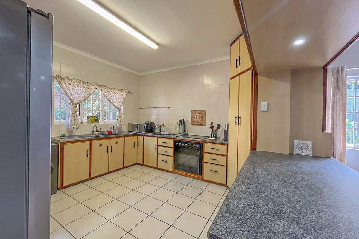 A functional kitchen featuring tiled flooring, laminate countertops, built-in cabinetry, and an integrated oven with a hob.