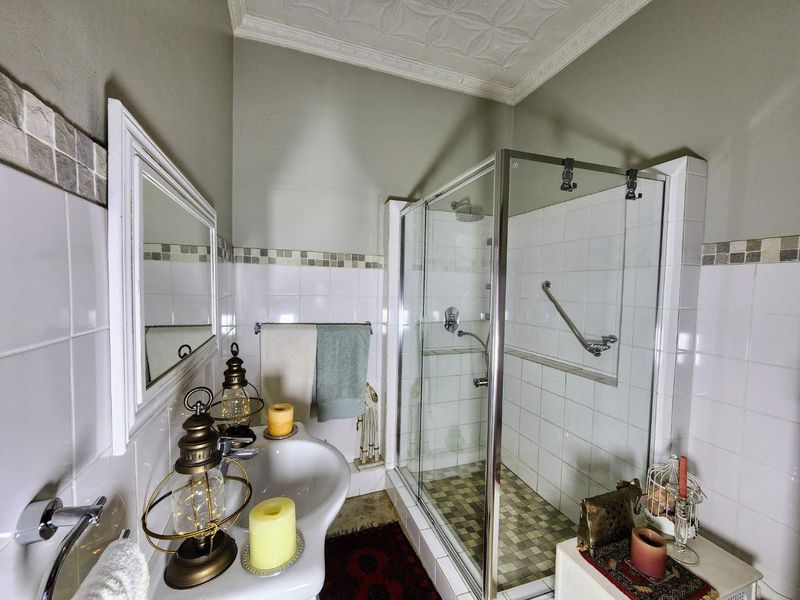 A functional bathroom featuring a glass-enclosed shower with a grab bar, a pedestal basin, and decorative ceiling cornicing.