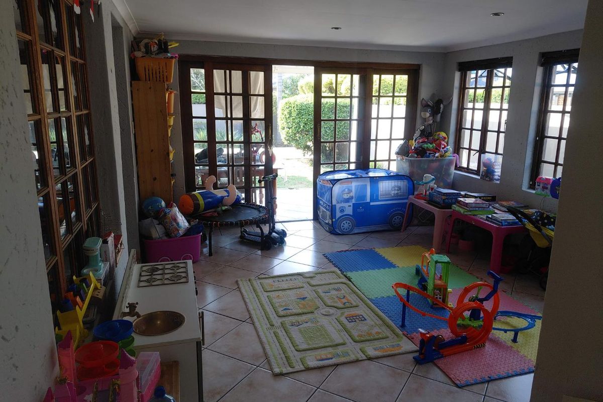 A sunlit living area featuring tiled flooring, recessed downlights, and large french doors providing direct access to the outdoor patio area.