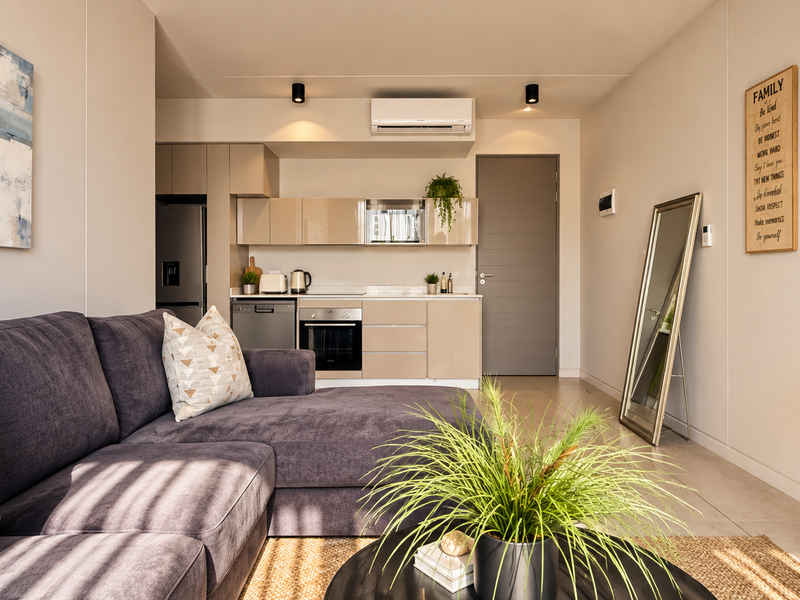 Modern open-plan living area featuring a compact kitchen with built-in cabinetry, integrated oven, and a split-system air conditioner.