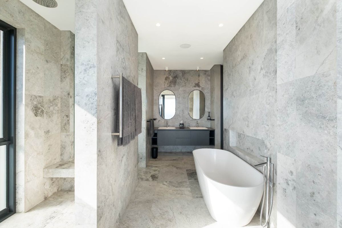 Modern luxury bathroom featuring a freestanding bathtub, double vanity with stone finishes, and a spacious walk-in shower with premium stone tiling.