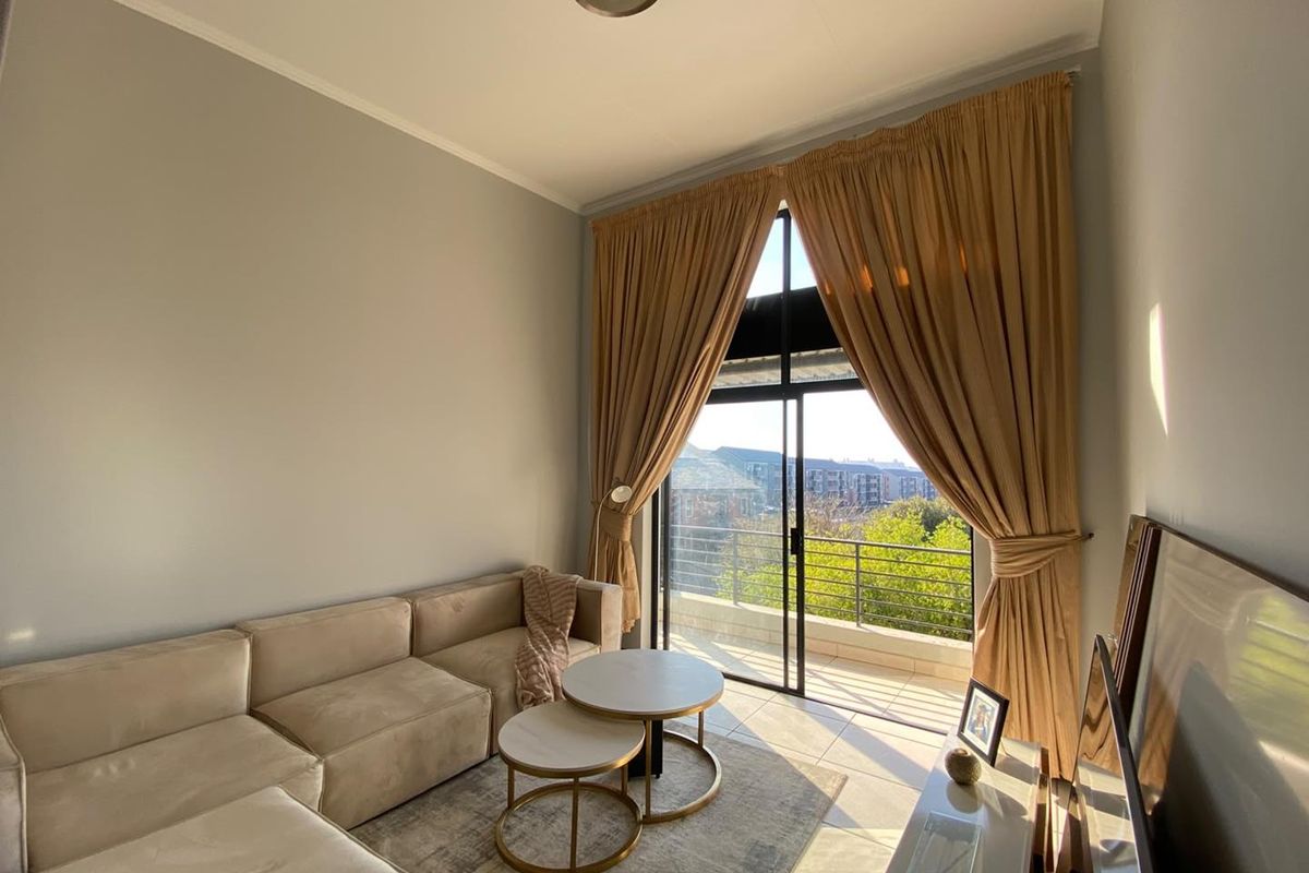 Bright living room featuring high ceilings, tiled flooring, and large sliding glass doors opening onto a private balcony with neighborhood views.