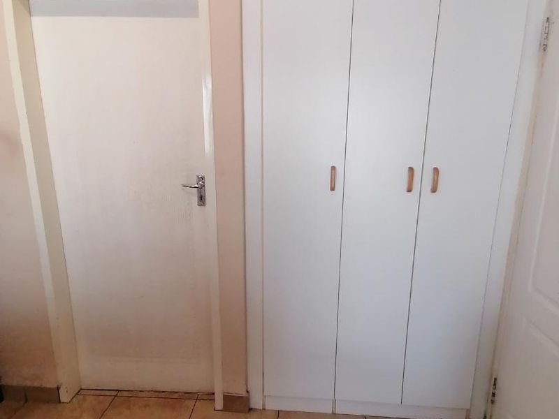 A bedroom interior featuring built-in cupboards and tiled flooring, presenting a clean and neutral space ready for personalization.