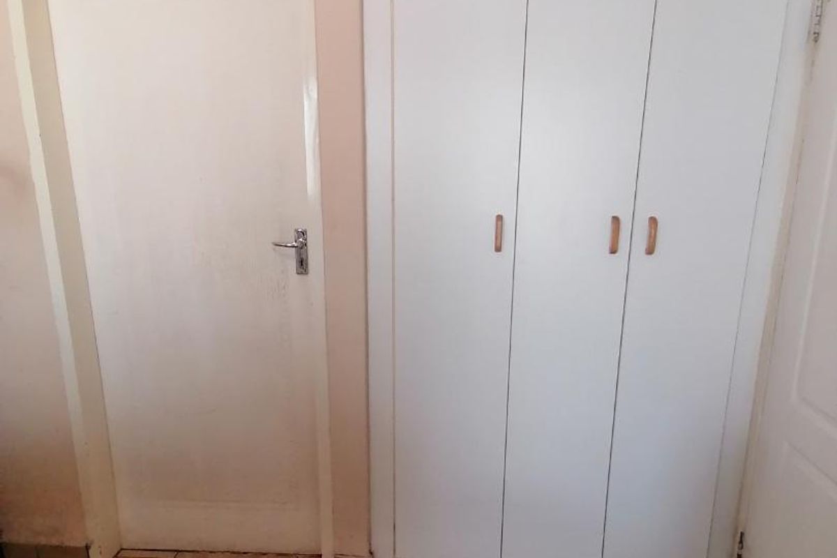 A bedroom interior featuring built-in cupboards and tiled flooring, presenting a clean and neutral space ready for personalization.