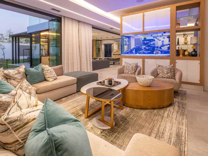 Spacious modern living room featuring a large built-in aquarium, recessed lighting, and expansive sliding glass doors that open to the outdoor area.