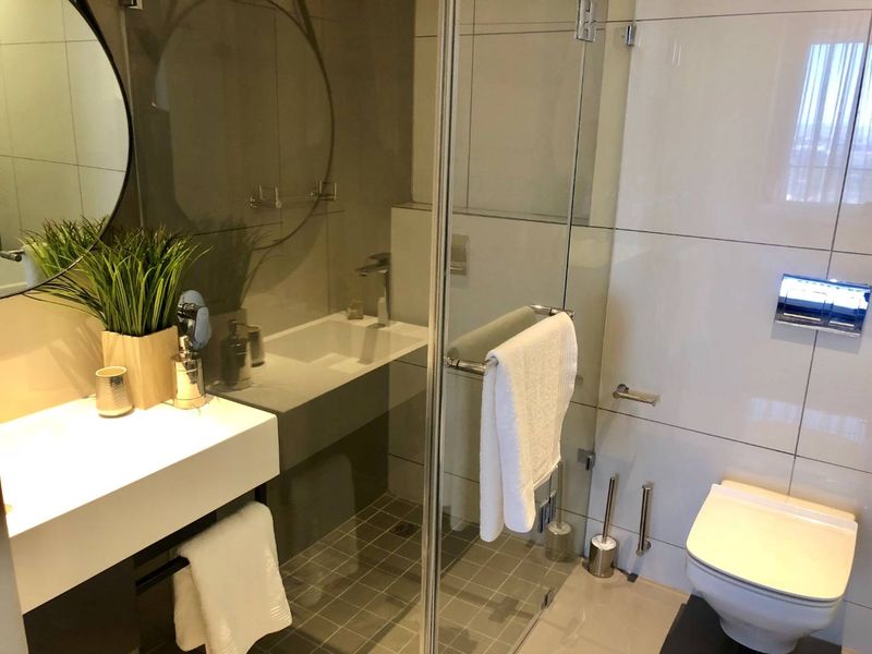 Modern bathroom featuring a wall-mounted vanity, glass shower enclosure, and wall-hung toilet with high-quality tiled finishes throughout.