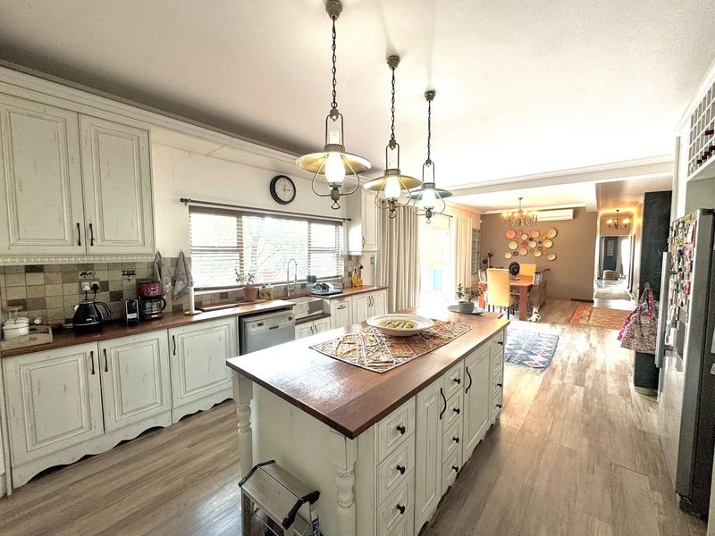Spacious open-plan kitchen featuring a central island with wooden countertops, classic cabinetry, and integrated lighting, flowing seamlessly into the dining and living areas.