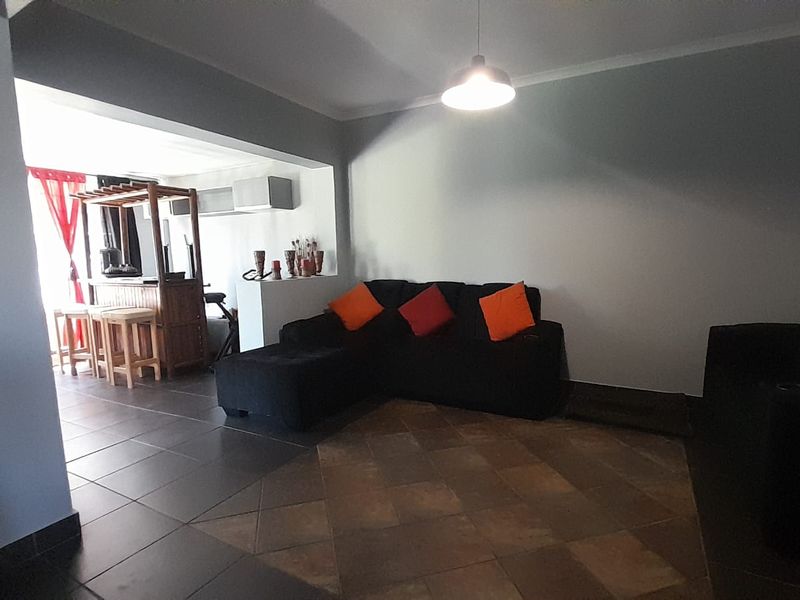 An open-plan living area featuring tiled flooring, a breakfast bar, and neutral wall finishes, creating a functional and connected space.