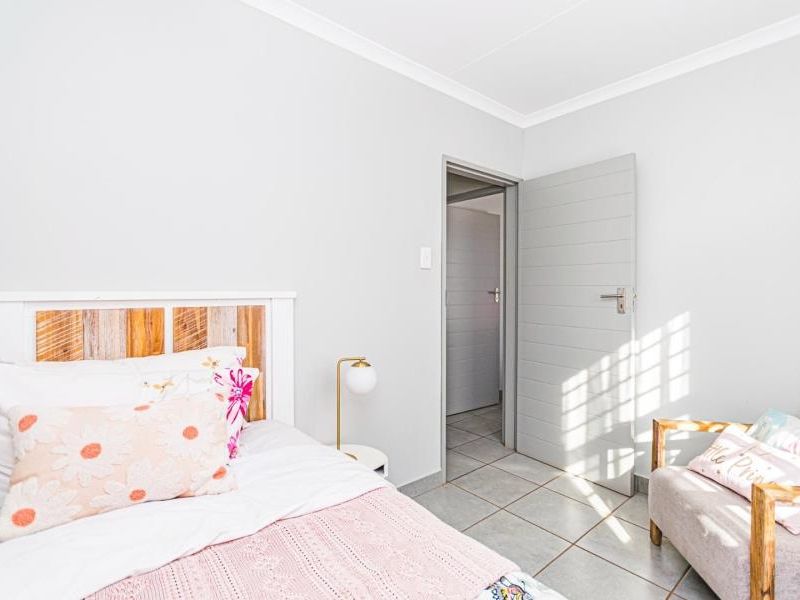 A bright bedroom featuring neutral wall finishes, tiled flooring, and a coved ceiling, providing a clean and functional living space.