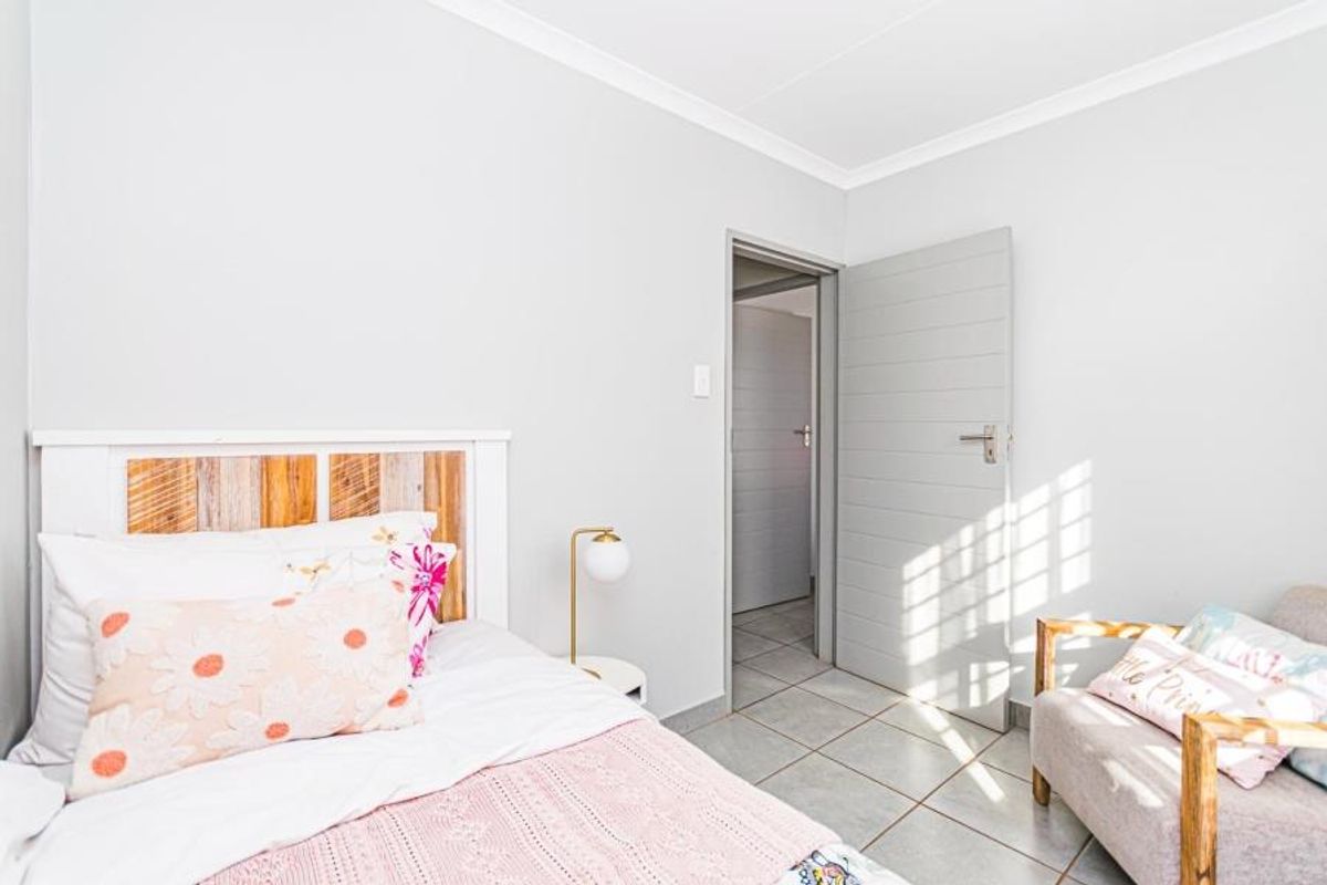 A bright bedroom featuring neutral wall finishes, tiled flooring, and a coved ceiling, providing a clean and functional living space.