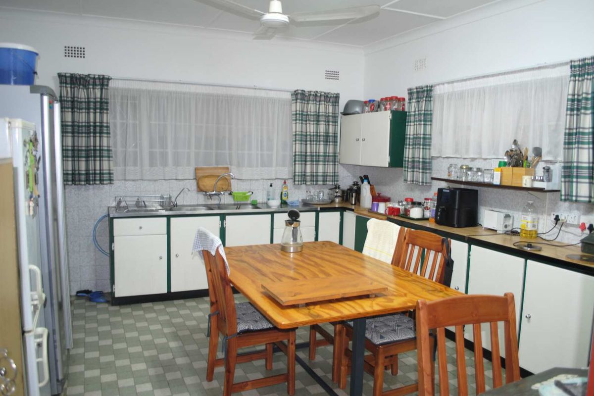 A functional kitchen featuring dated cabinetry, a double basin sink, and vinyl flooring, offering potential for a modern renovation.