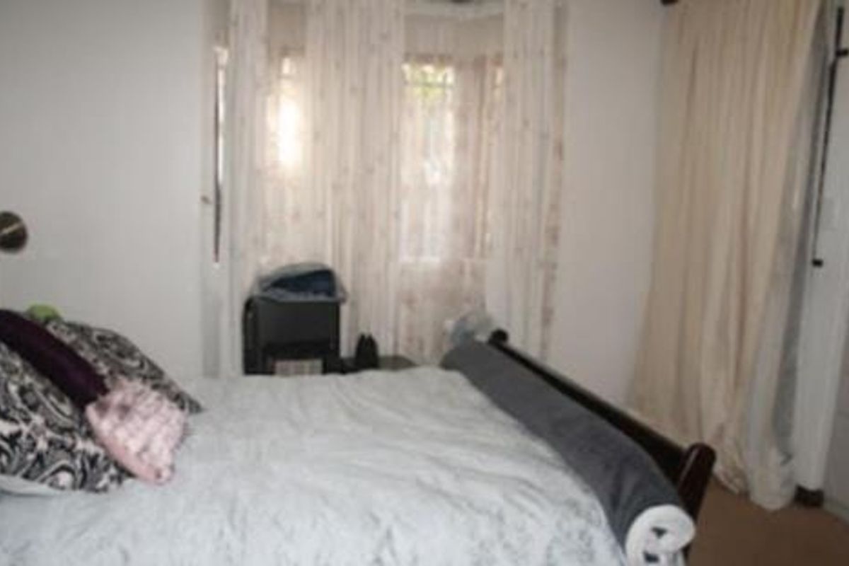 A bedroom featuring a bay window with curtains and neutral wall finishes.