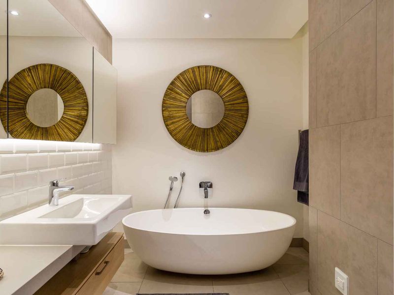 Modern bathroom featuring a sleek freestanding bathtub, wall-mounted basin with vanity storage, and elegant subway tile detailing with recessed lighting.