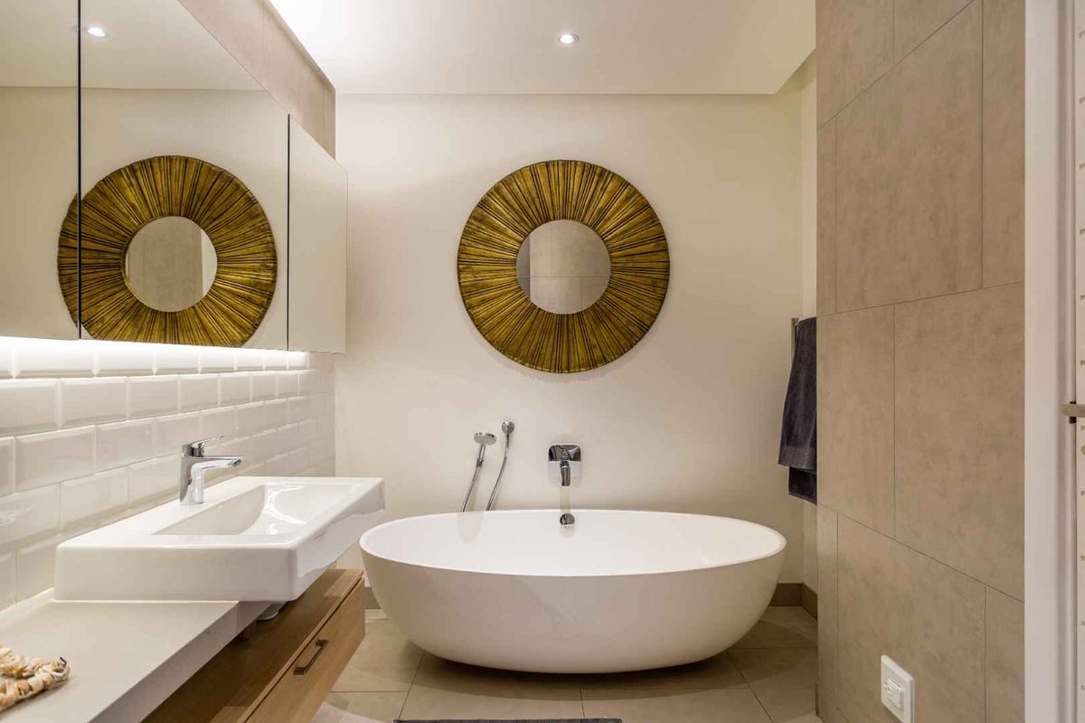 Modern bathroom featuring a sleek freestanding bathtub, wall-mounted basin with vanity storage, and elegant subway tile detailing with recessed lighting.
